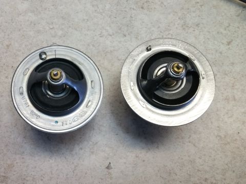 2008 Hyundai Accent - Two automotive thermostats are shown side-by-side on a flat surface.