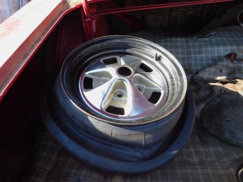1968 Mercury Cougar - Spare tire and wheel are visible in the trunk of a red car with a plaid liner.