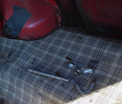 1968 Mercury Cougar - The trunk interior shows a jack and lug wrench resting on the plaid carpet, with red painted metal visible above.