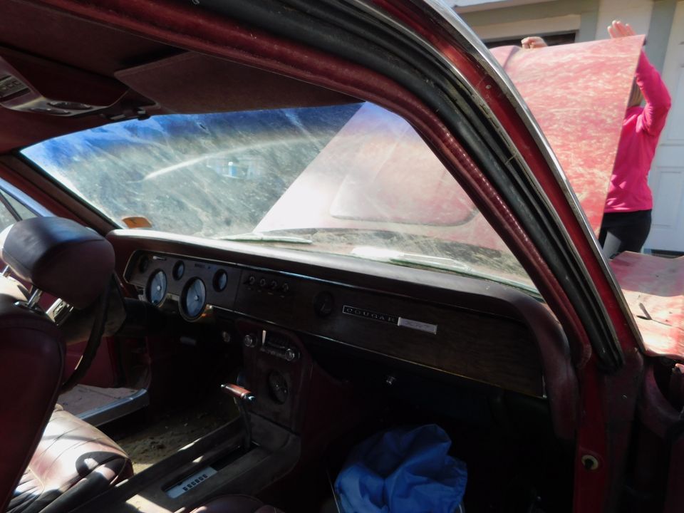 Red 1968 Mercury Cougar interior with wood grain dashboard, round gauges, and a "COUGAR" emblem
