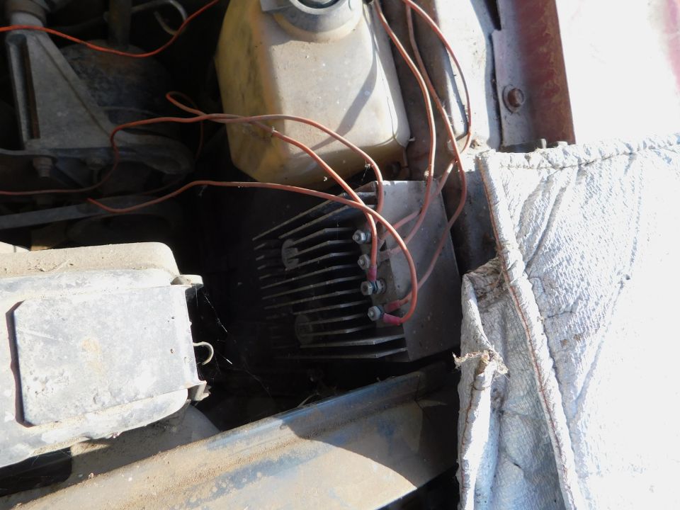 Close-up of a car's engine bay showing a voltage regulator with wires connected