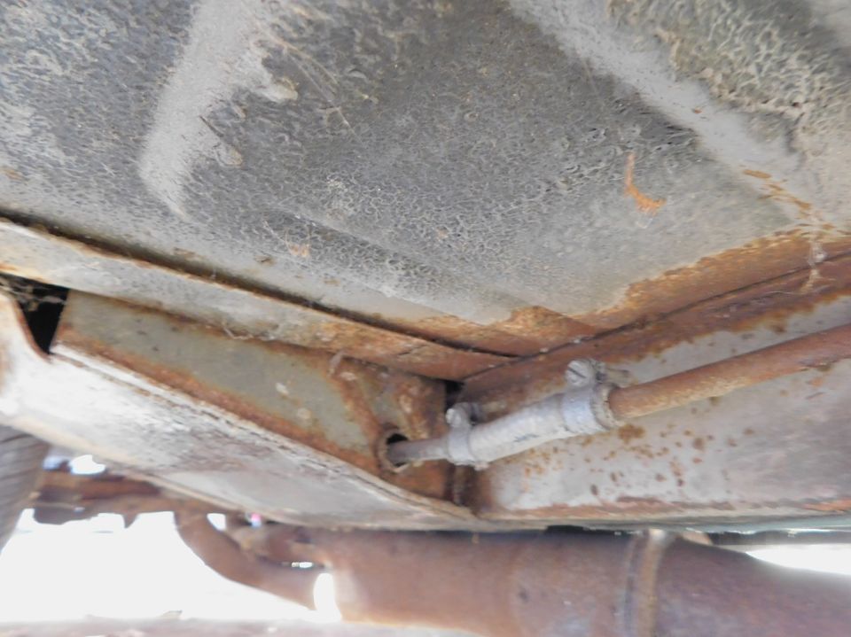 Close-up of rusty underbody frame and fuel line on a vehicle