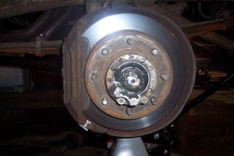 1973 Ford F-250 - Close-up of a vehicle's front wheel hub and brake assembly, supported by a jack stand.