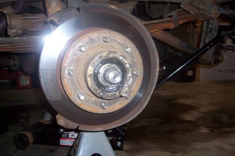 1973 Ford F-250 - Close-up of a truck's hub and brake rotor assembly, supported by jack stands.