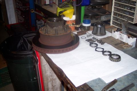1973 Ford F-250 - Disassembled front wheel hub and brake rotor assembly, including bearings and hardware, laid out on a white cloth on a workbench.