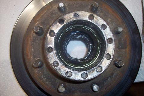 1973 Ford F-250 - A close-up view of a vehicle's brake rotor and hub assembly, showing signs of wear and grease accumulation.