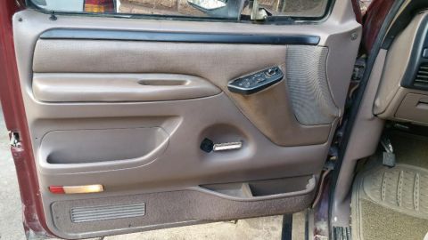 1996 Ford Bronco - Interior view of a car door panel, showing the window controls and door handle.