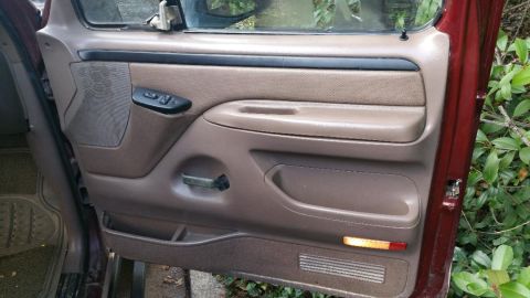 1996 Ford Bronco - Interior door panel of a vehicle, showing brown upholstery and controls.