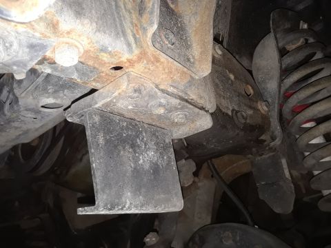 1985 Ford Bronco - Close-up of vehicle undercarriage showing frame rust and suspension parts, with a SuperMotors watermark.
