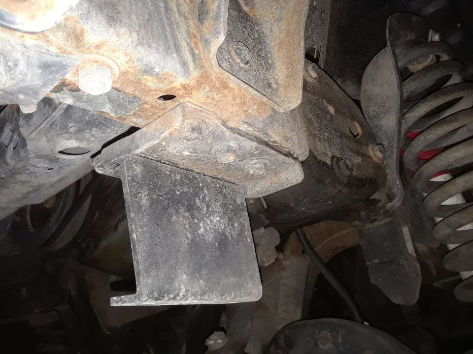 Undercarriage view of rusty frame and suspension components, with SuperMotors logo