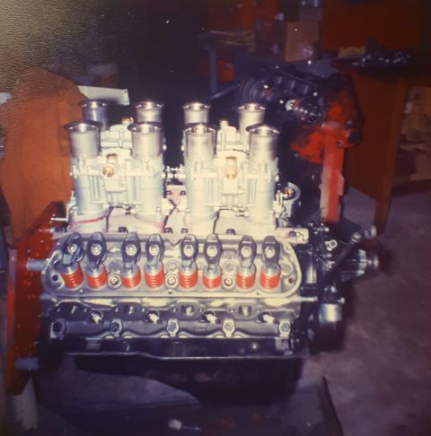 1973 Ford Mustang - A V8 engine with a custom intake manifold six carburetors is shown in a workshop setting.