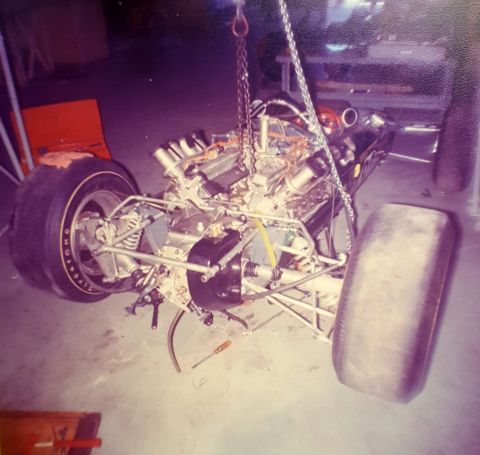 1973 Ford Mustang - The engine and chassis of a race car are suspended by chains, with a screwdriver on the floor nearby.