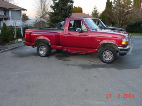 1992 Ford F-150 - This red 1992 Ford F-150 pickup truck is shown from a 3q-front angle, with another vehicle visible behind it.