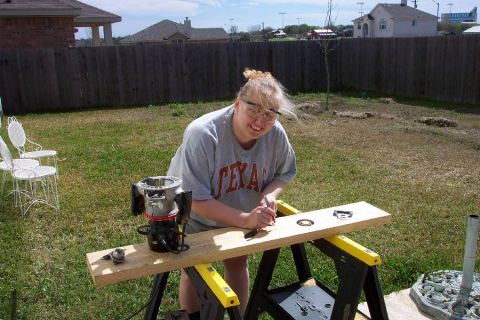 1992 Ford Bronco - Woman working on a wooden board with a router in a backyard setting.