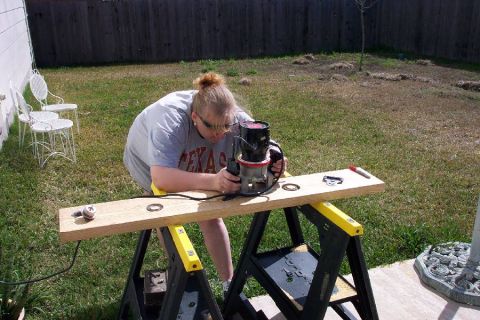 1992 Ford Bronco - A person works on a wooden plank with a router in an outdoor setting.