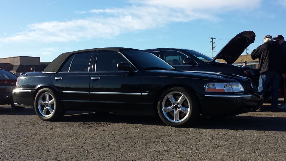 Black Mercury Grand Marquis with vinyl top and custom wheels parked outside.