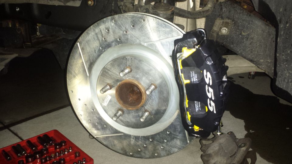 Drilled and slotted front brake rotor with black S55 brake caliper installed on truck