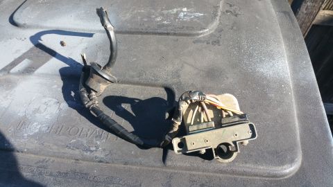 1996 Ford Bronco - A close-up view of a wiring harness with a fuse box or relay module, likely from a 1996 Ford Bronco. The part is resting on a textured gray…