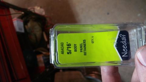 1996 Ford Bronco - A hand holds a package of 5/16" body panel retainers. The package is clear plastic with a bright green label inside.