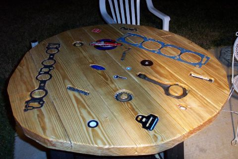 1992 Ford Bronco - Engine parts are laid out on a wooden table, resembling a unique display or workbench.
