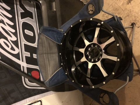 1995 Ford F-150 - A black and silver aftermarket wheel is shown resting on a blue camping chair. The wheel has a multi-spoke design with polished accents and…