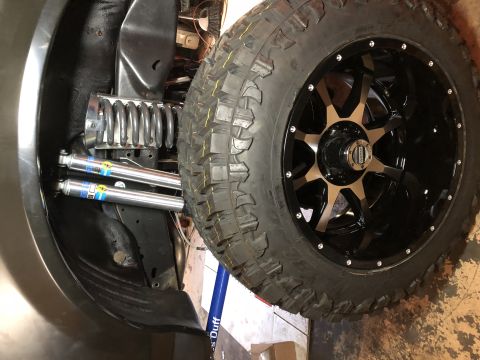 1995 Ford F-150 - Close-up view of the suspension components and a large off-road tire mounted on a black and bronze aftermarket wheel. The suspension includ…