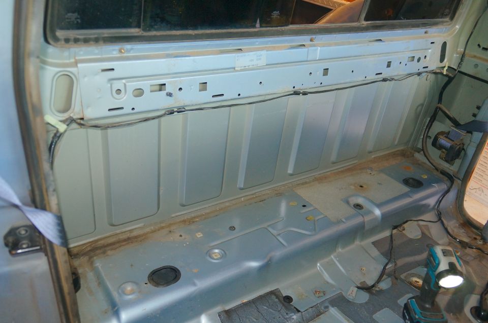 Bare painted interior rear cab wall and floor of a truck with seat removed during restoration