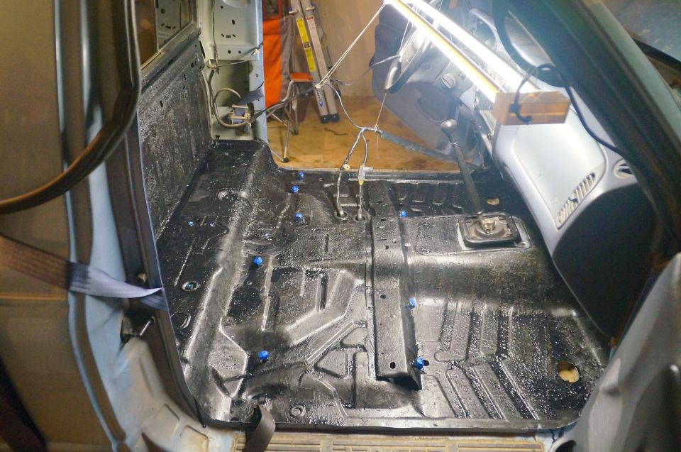 Interior floor of a vehicle with black protective coating and blue caps.