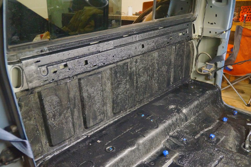 Black spray liner in a pickup truck bed and cab floor with blue caps.
