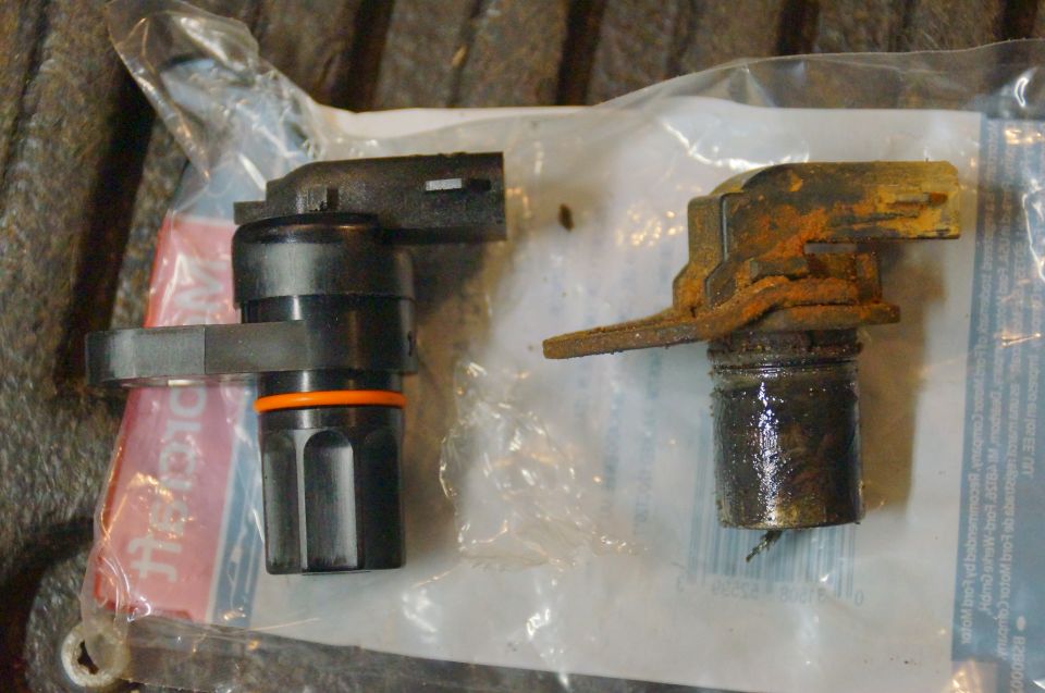 New black automotive sensor next to a rusted, dirty old sensor