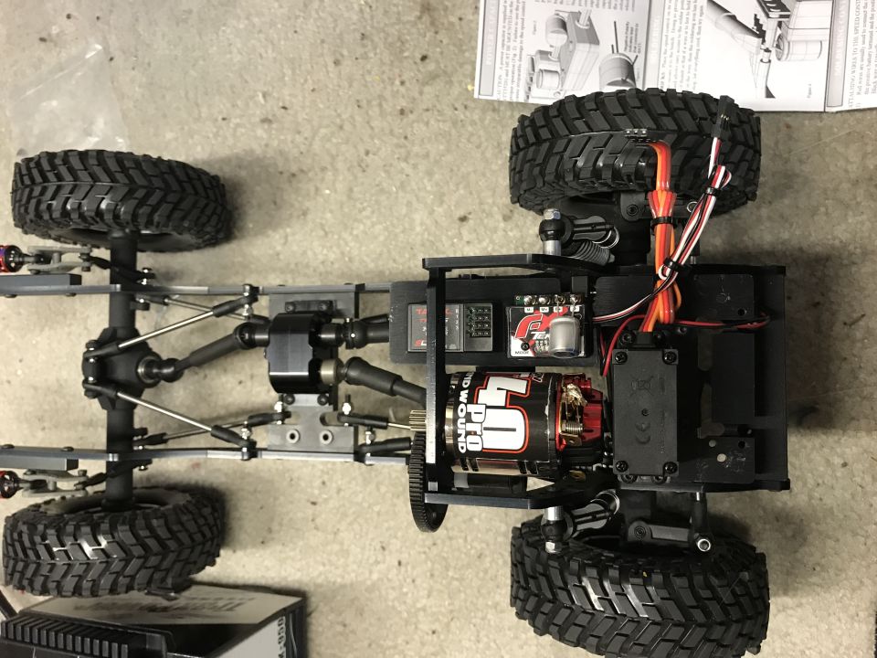 RC car chassis with motor, ESC, servo, and suspension visible.