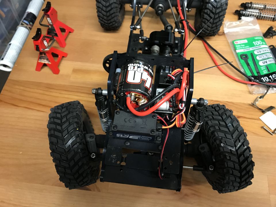 Remote-control rock crawler chassis with motor, tires, and wiring.