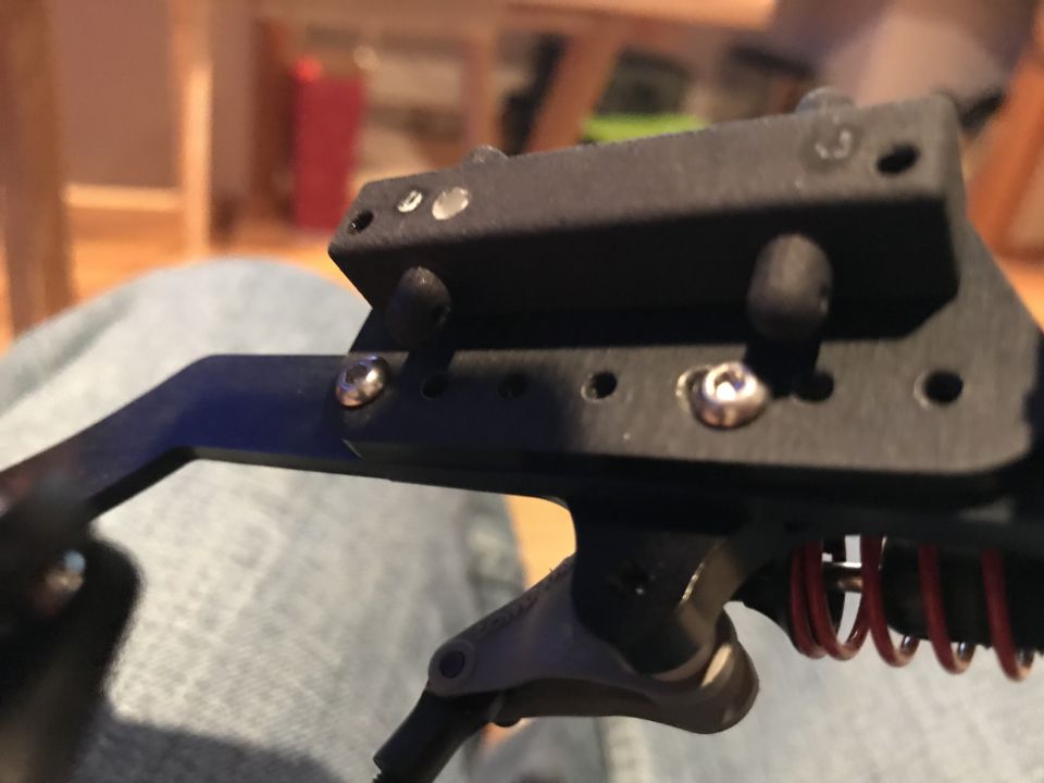 Black metal bracket with silver screws and red springs, part of a vehicle modification.