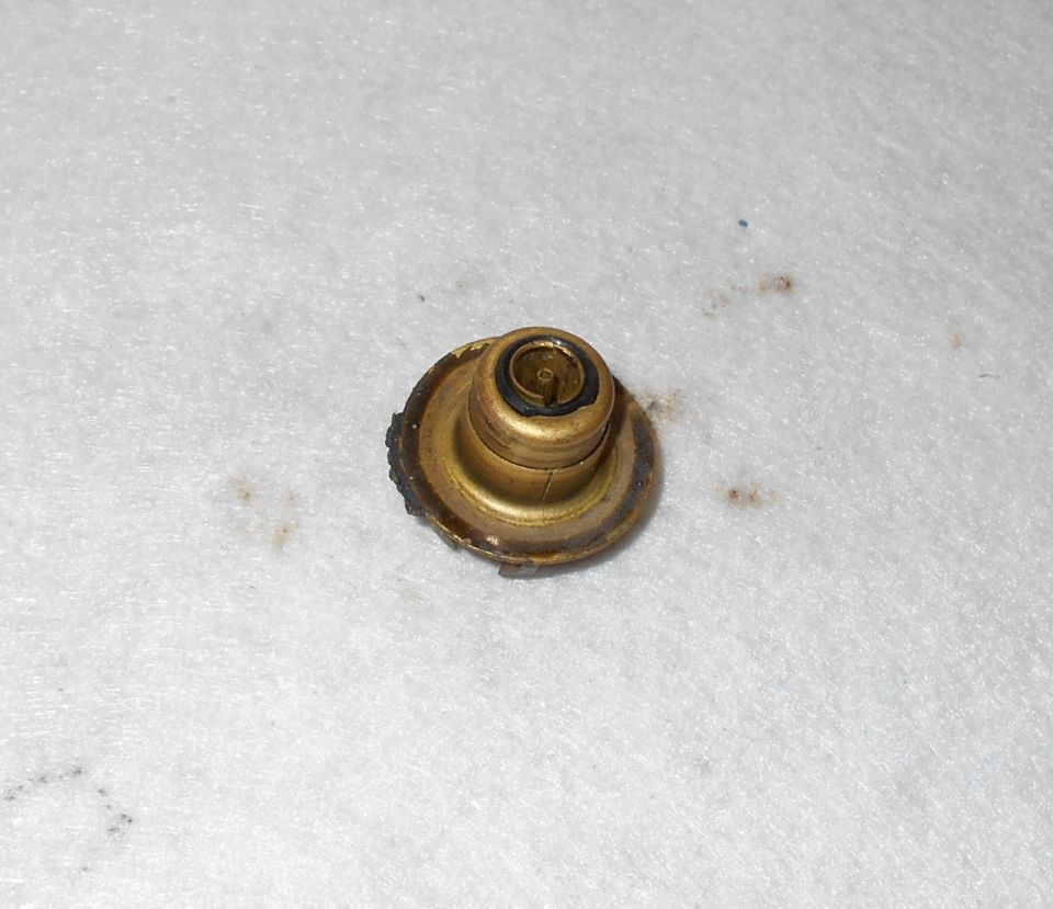 Brass thermostat with black rubber seal on white textured surface