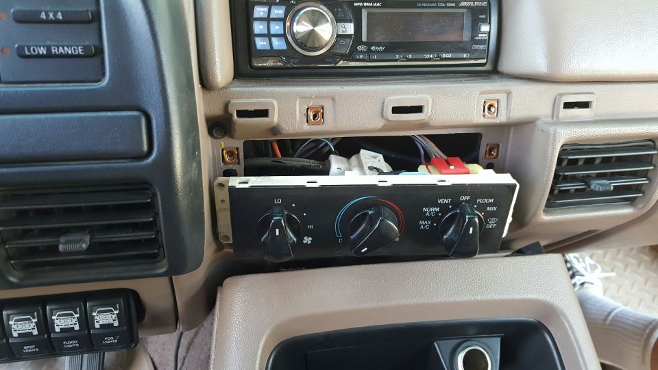 1996 Ford Bronco interior center console with climate controls removed, stereo, and auxiliary light switches.