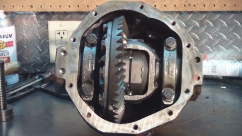 1996 Ford Bronco - A close-up view of an open differential housing, revealing the ring gear and spider gears. Tools and a can of spray paint are visible in th…