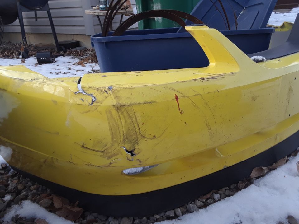 Damaged yellow front bumper with cracks and scrapes.