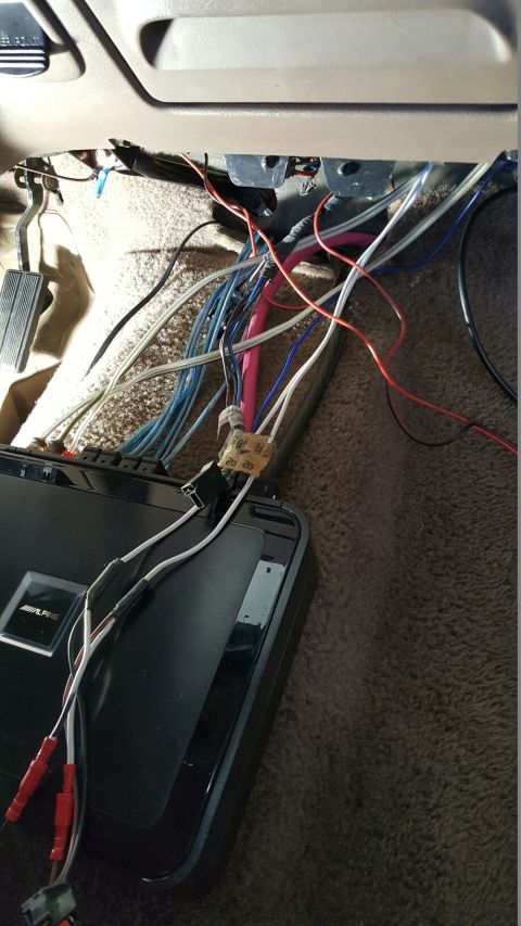 1996 Ford Bronco - Exposed wiring and an amplifier are visible on the floor of a car's interior.