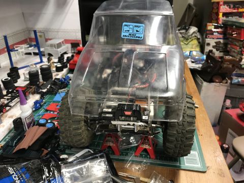 1989 Ford Bronco - A clear RC car body, possibly a Ford Bronco, sits on jack stands with a winch attached to the front bumper.