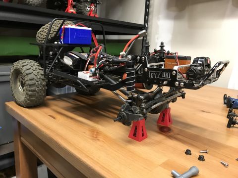 1989 Ford Bronco - RC car chassis assembly with visible electronics and suspension parts on a wooden workbench.