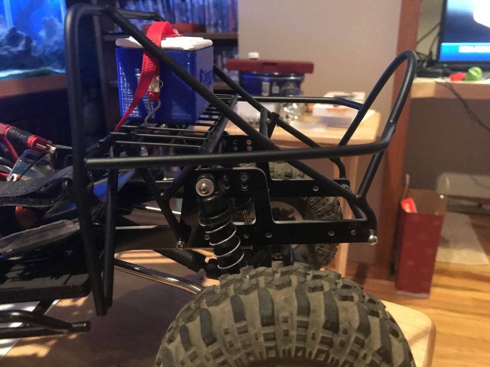 RC rock crawler chassis detail showing suspension, shock absorber, and tire