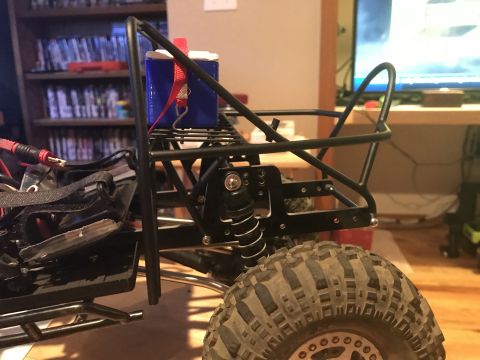 1989 Ford Bronco - Close-up of an RC rock crawler's chassis, showing suspension and a battery secured to the roll cage.