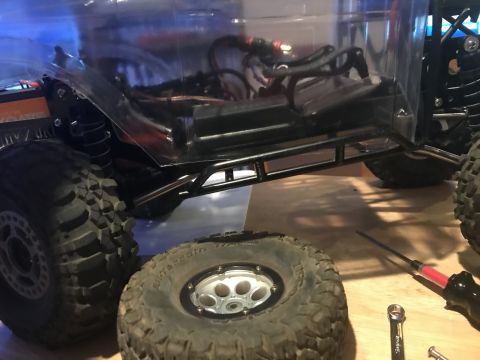 1989 Ford Bronco - Close-up of an RC car's chassis, showing exposed wiring, suspension components, and a roll cage.