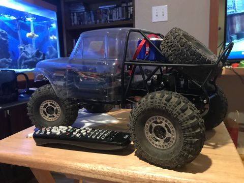 1989 Ford Bronco - A clear plastic body of a classic pickup truck sits on a custom roll cage chassis with large off-road tires. A remote control is placed in…