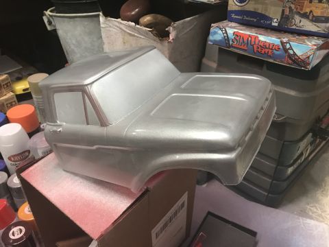 1989 Ford Bronco - A silver, unpainted pickup truck body sits on top of a cardboard box. Several cans of spray paint are visible around the body.