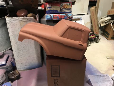 1989 Ford Bronco - A partially assembled, unpainted model truck cab sits on top of a cardboard box. The model is a light brown color and appears to be a vinta…
