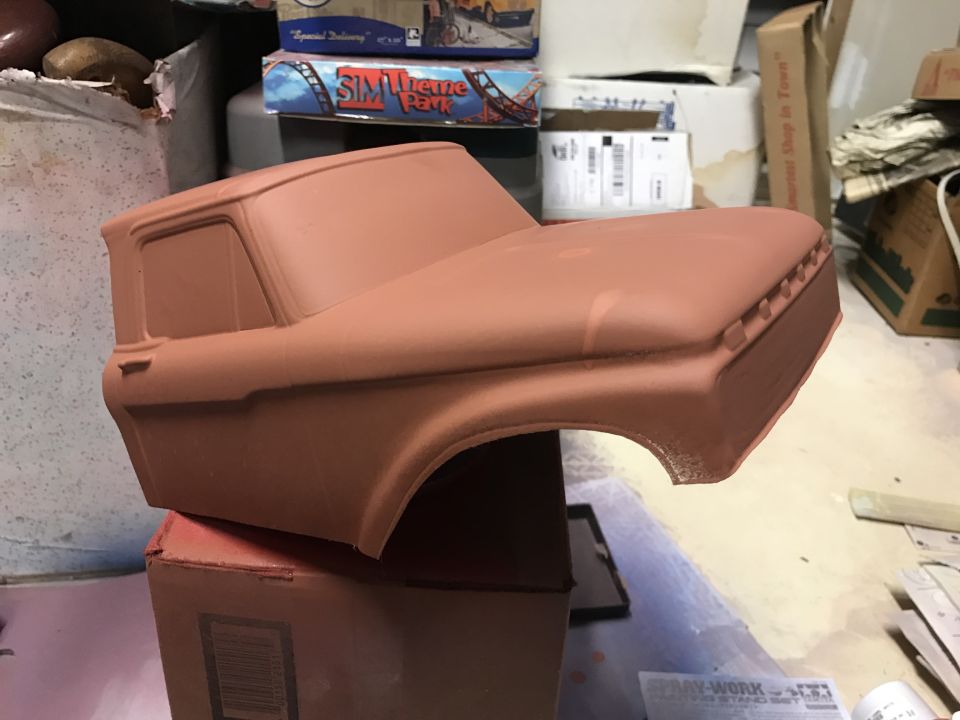 Unpainted red model pickup truck body resting on a cardboard box.