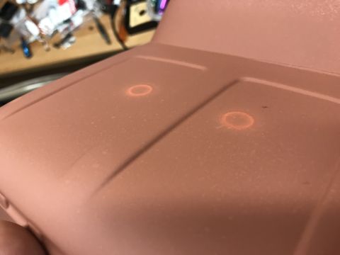 1989 Ford Bronco - A close-up, angled view of the hood of a vehicle, painted a matte reddish-brown. Two circular, orange-glowing marks are visible on the hood…