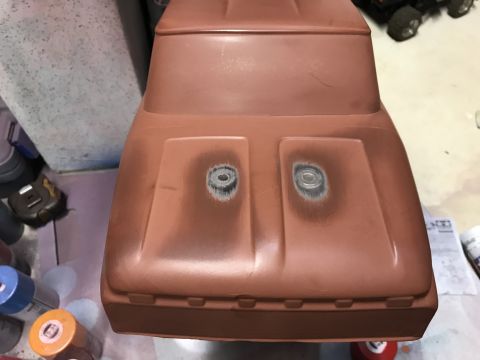 1989 Ford Bronco - The front hood of a reddish-brown, unpainted RC car body is shown. Two circular indentations, likely for headlights, are visible on the hoo…