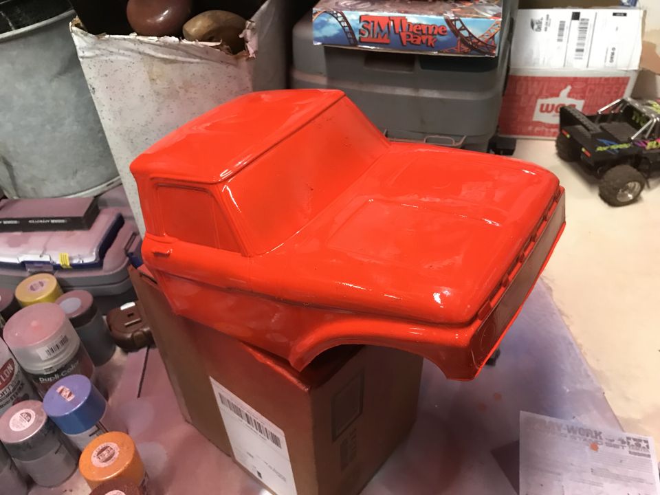 Orange truck body on a box with spray paint cans.